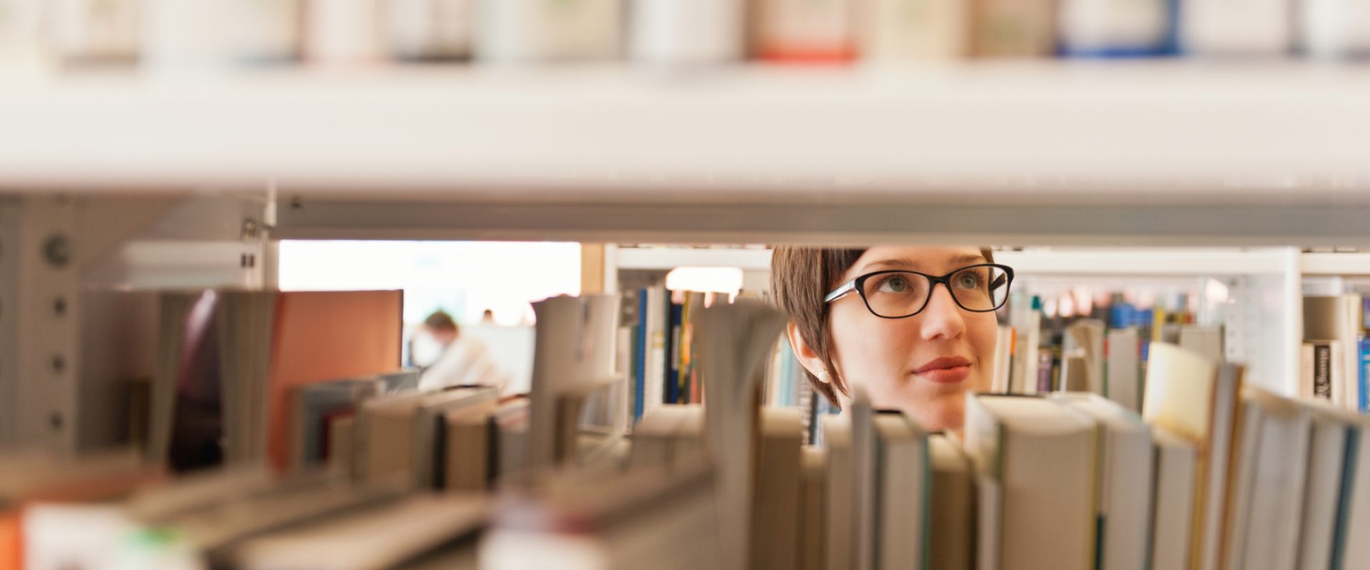 a glimpse of a woman through the library stacks